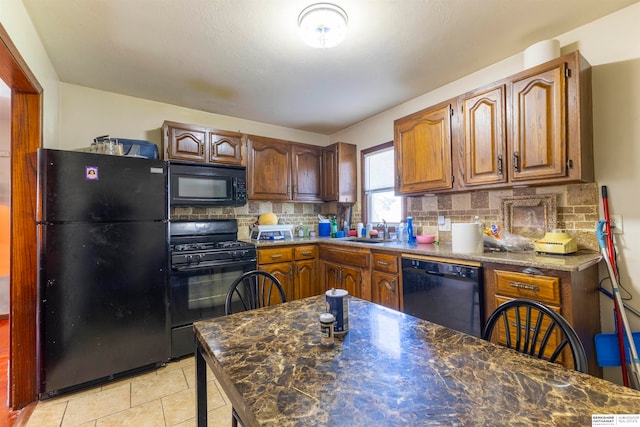 kitchen featuring black appliances, tasteful backsplash, light tile patterned floors, and sink