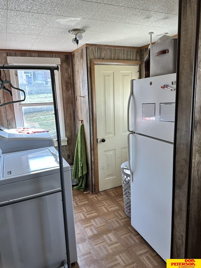 kitchen featuring independent washer and dryer, parquet floors, wooden walls, and white fridge