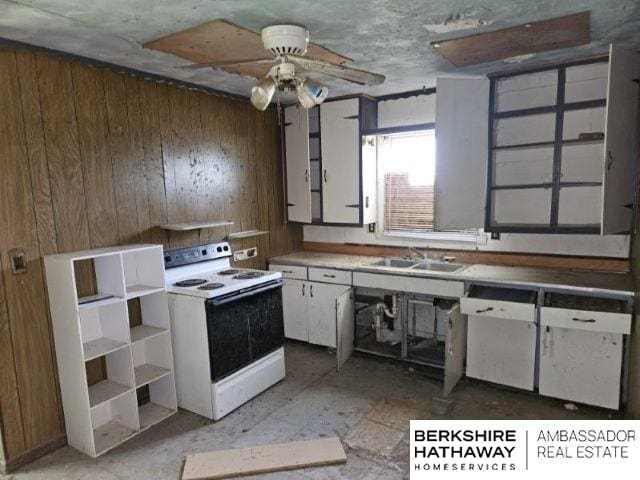 kitchen featuring sink, wood walls, white cabinetry, ceiling fan, and white range with electric cooktop