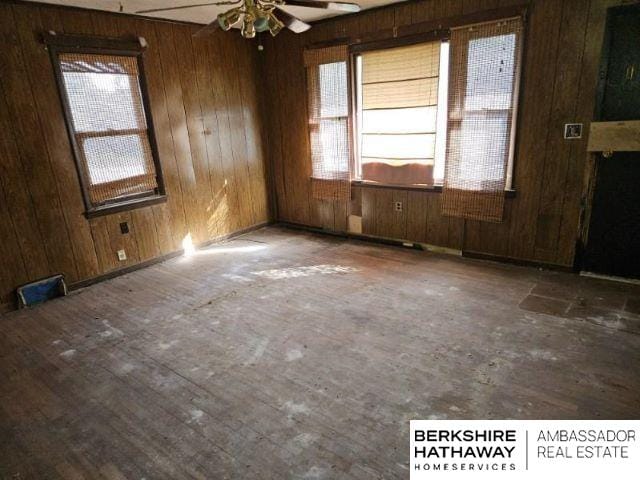 unfurnished room featuring wooden walls, ceiling fan, and hardwood / wood-style flooring