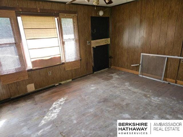 spare room featuring wood walls and ceiling fan