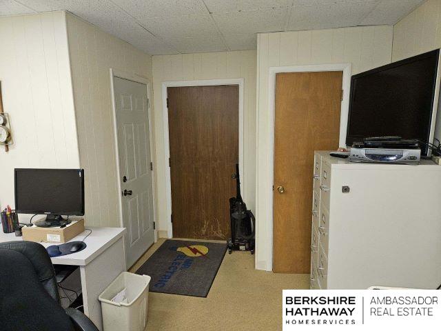 office area featuring light carpet and wood walls