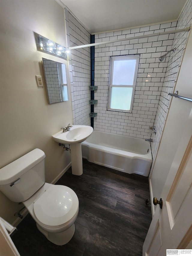 bathroom featuring wood-type flooring, tiled shower / bath combo, and toilet