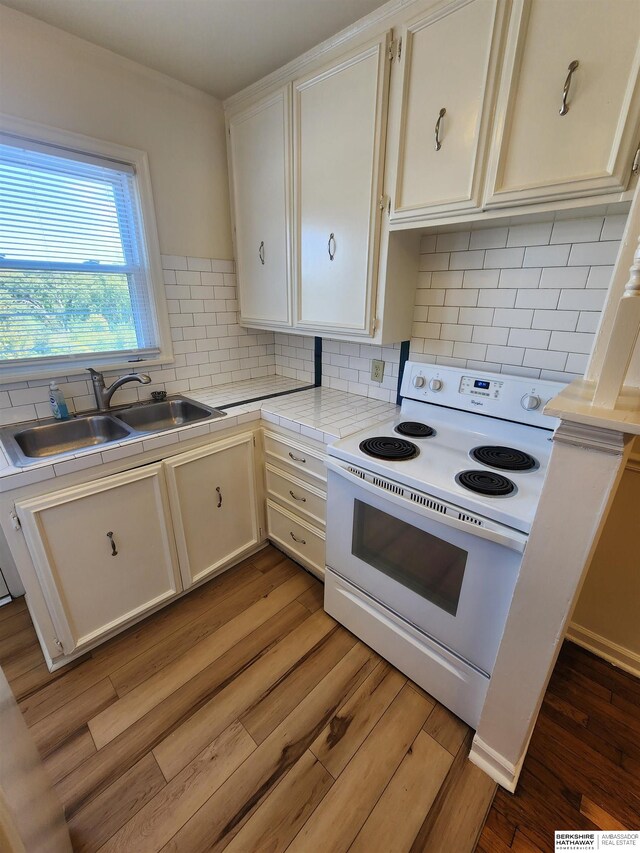 kitchen with decorative backsplash, white cabinets, white range with electric stovetop, hardwood / wood-style floors, and sink