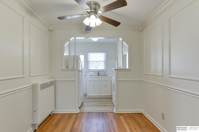 interior space featuring light hardwood / wood-style floors, crown molding, radiator, ceiling fan, and sink