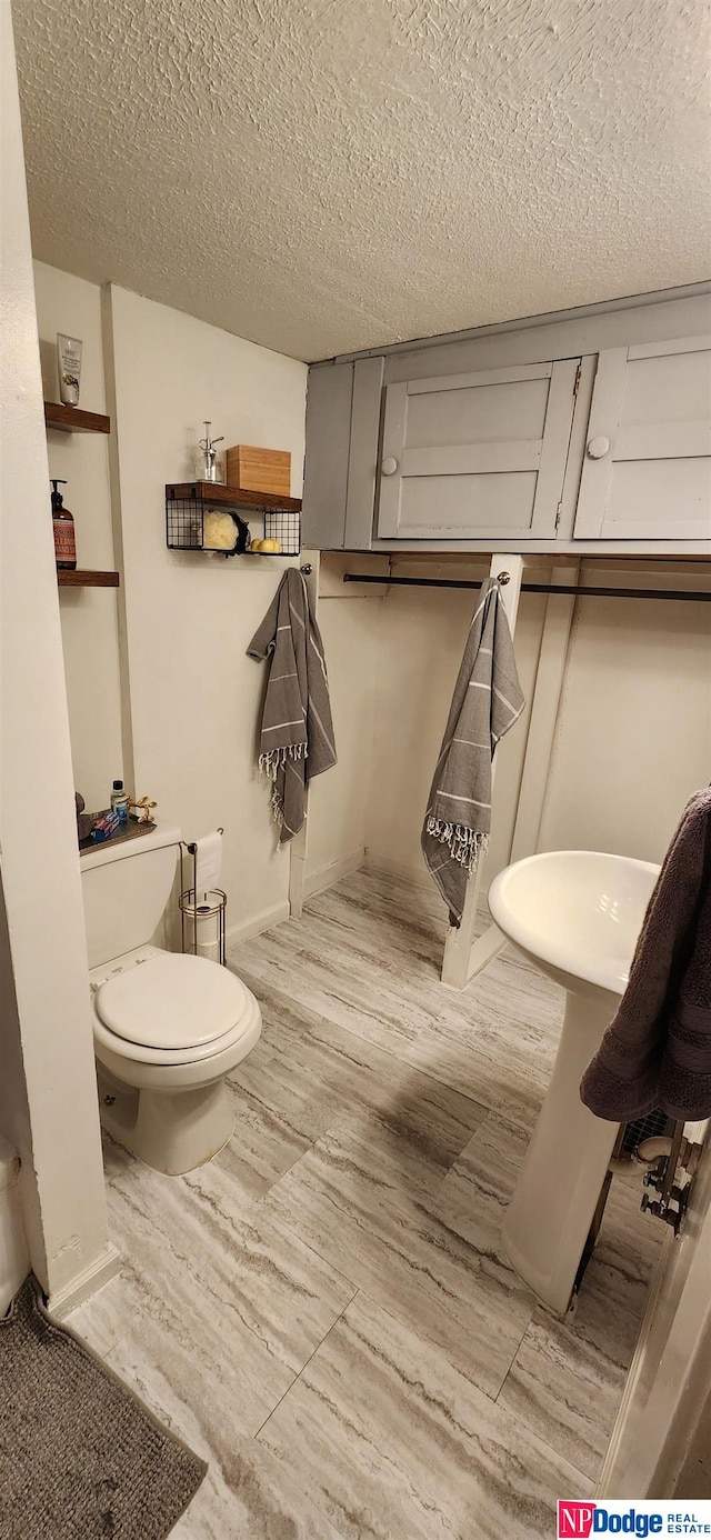 bathroom featuring a textured ceiling, hardwood / wood-style floors, and toilet