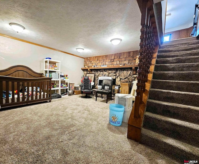 interior space featuring a textured ceiling, crown molding, a stone fireplace, and carpet floors