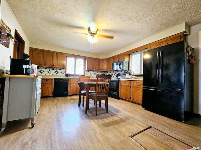 kitchen with ceiling fan, a textured ceiling, backsplash, black appliances, and light hardwood / wood-style floors