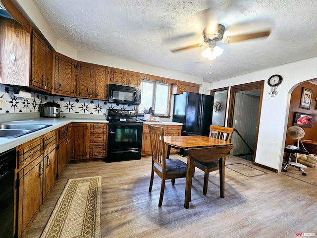 kitchen with decorative backsplash, light wood-type flooring, black appliances, a textured ceiling, and ceiling fan