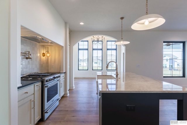 kitchen featuring white cabinets, pendant lighting, high end stainless steel range, dark wood-type flooring, and decorative backsplash