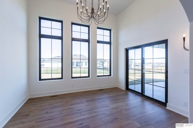 unfurnished room featuring a notable chandelier, high vaulted ceiling, and dark wood-type flooring