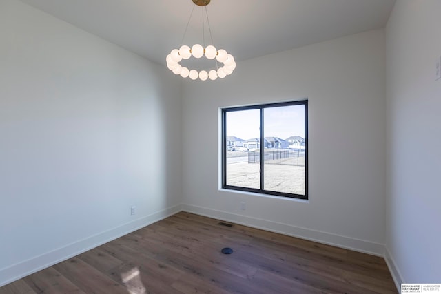 unfurnished room featuring an inviting chandelier and dark hardwood / wood-style floors