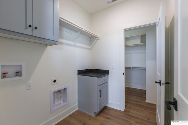 clothes washing area featuring cabinets, hookup for an electric dryer, washer hookup, and light wood-type flooring