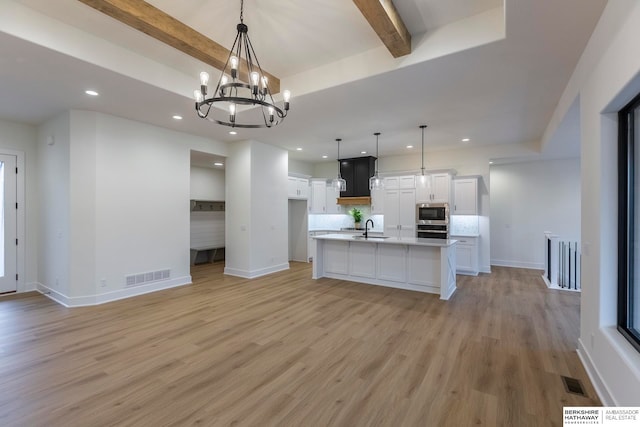 kitchen featuring white cabinets, beamed ceiling, hanging light fixtures, and light hardwood / wood-style floors