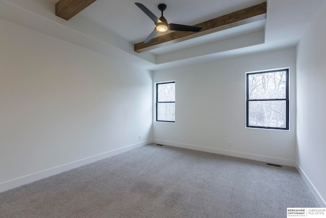 empty room with light carpet, beam ceiling, ceiling fan, and a healthy amount of sunlight