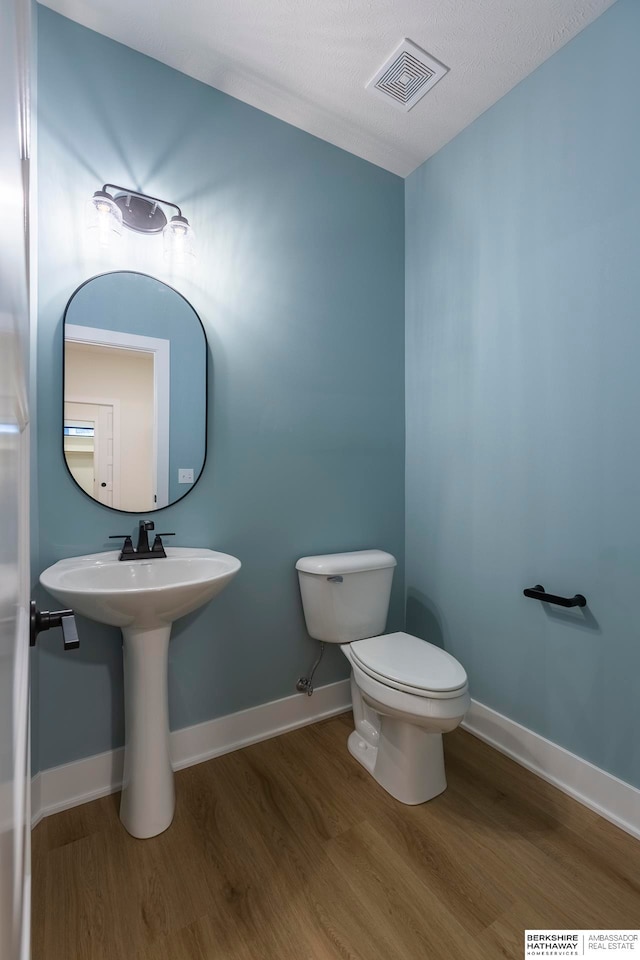 bathroom with a textured ceiling, toilet, and hardwood / wood-style flooring