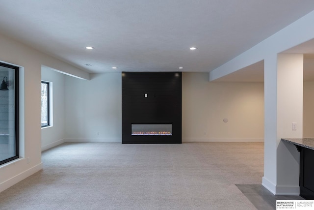 unfurnished living room with light carpet and a large fireplace