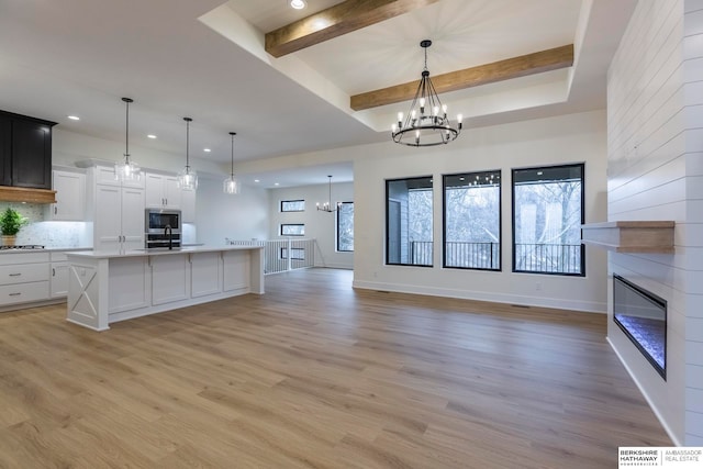 kitchen featuring light wood-type flooring, white cabinetry, beamed ceiling, and decorative light fixtures