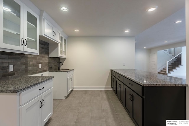 kitchen featuring light tile patterned floors, sink, tasteful backsplash, white cabinetry, and dark stone counters