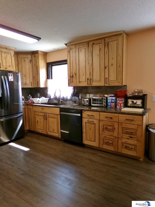 kitchen featuring a textured ceiling, appliances with stainless steel finishes, sink, and dark wood-type flooring