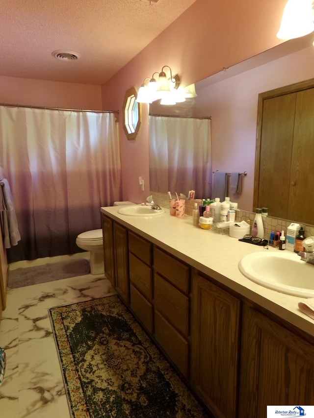 bathroom featuring a textured ceiling, vanity, toilet, and tasteful backsplash