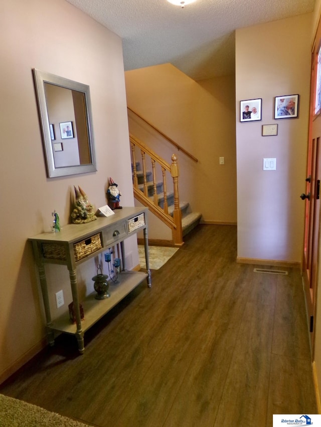 hallway with a textured ceiling and dark wood-type flooring