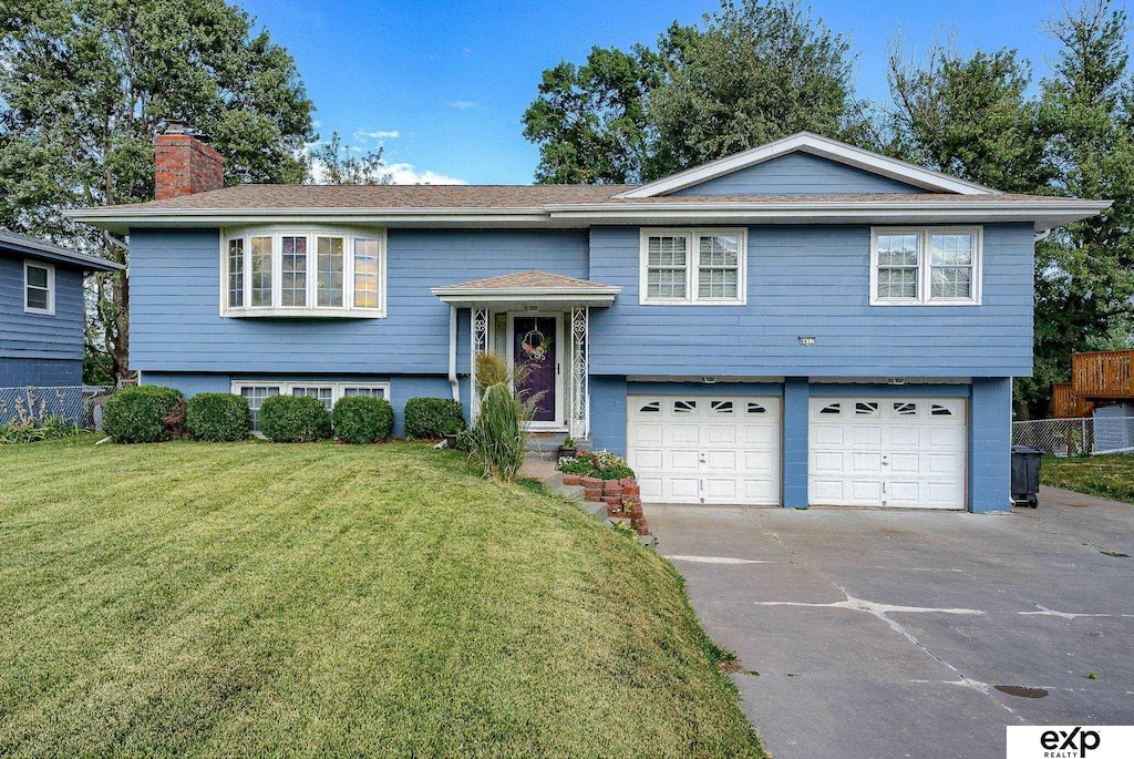 raised ranch with a garage and a front lawn
