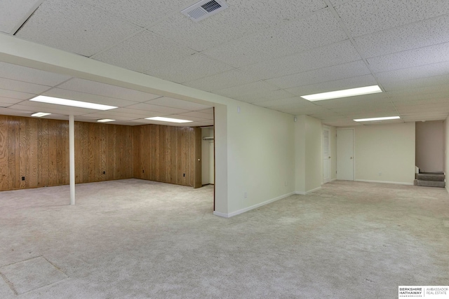 basement with wooden walls and light colored carpet