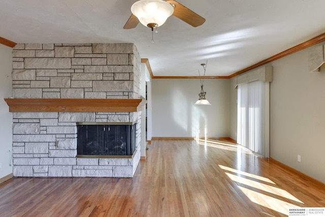 unfurnished living room with ornamental molding, ceiling fan, a stone fireplace, and hardwood / wood-style floors