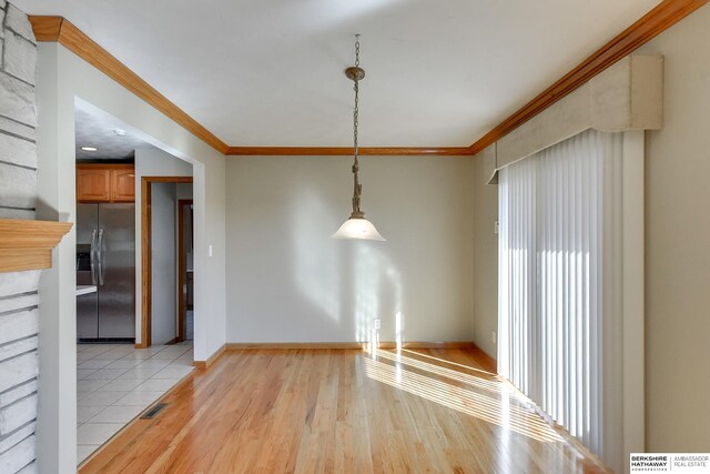 unfurnished dining area with light hardwood / wood-style floors and ornamental molding