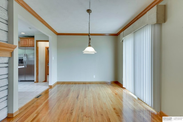 spare room featuring light wood-type flooring and crown molding