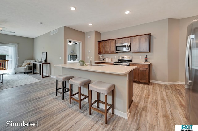 8501 Regent Ct, Lincoln, NE 68507 - kitchen with a breakfast bar, a kitchen island with sink, light hardwood / wood-style flooring, stainless steel appliances, and ceiling fan