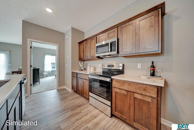8501 Regent Ct, Lincoln, NE 68507 - kitchen featuring a textured ceiling, light hardwood / wood-style flooring, stainless steel appliances, and a wealth of natural light