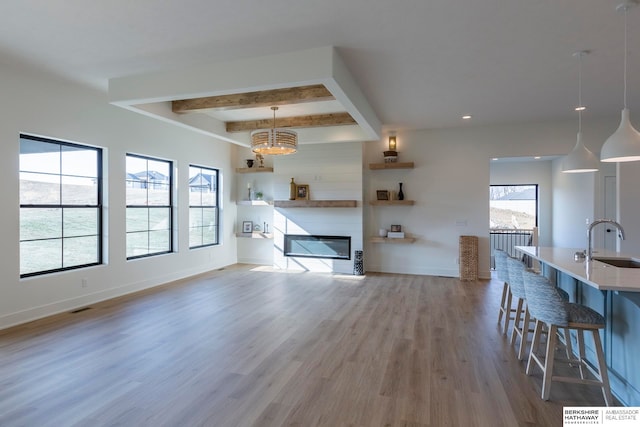 unfurnished living room with wood-type flooring, a fireplace, beam ceiling, and plenty of natural light