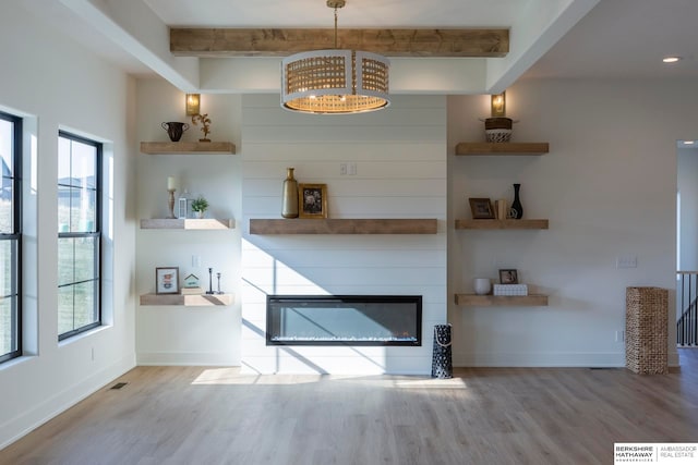 unfurnished living room with a chandelier, beamed ceiling, hardwood / wood-style flooring, and a fireplace