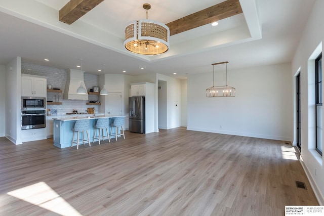 kitchen with hanging light fixtures, light hardwood / wood-style floors, white cabinetry, a kitchen island, and stainless steel appliances