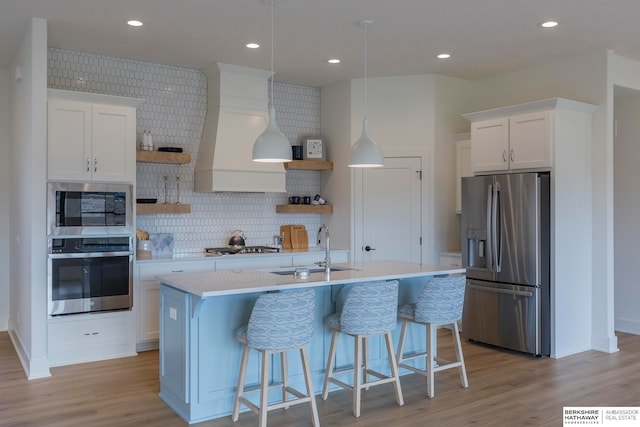 kitchen featuring sink, an island with sink, white cabinetry, light hardwood / wood-style flooring, and stainless steel appliances