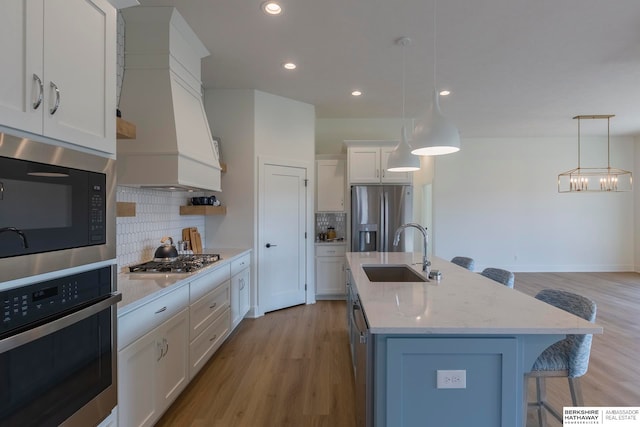 kitchen with stainless steel appliances, white cabinets, decorative light fixtures, and sink