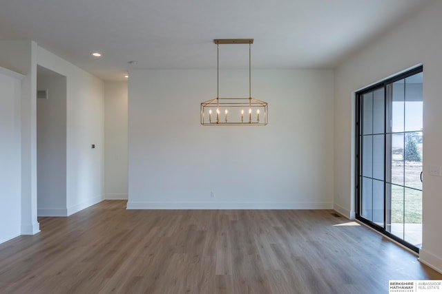 empty room with wood-type flooring and a chandelier