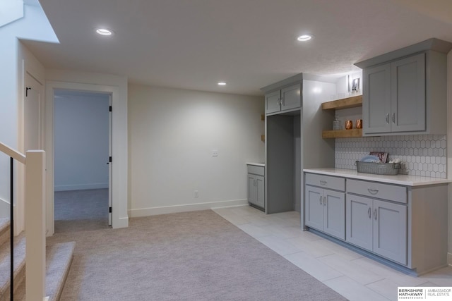 kitchen featuring light carpet, backsplash, and gray cabinetry