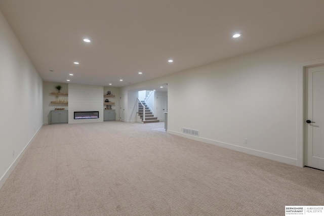 unfurnished living room with a large fireplace and light colored carpet