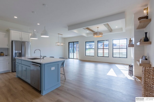 kitchen featuring appliances with stainless steel finishes, an island with sink, white cabinets, a healthy amount of sunlight, and sink