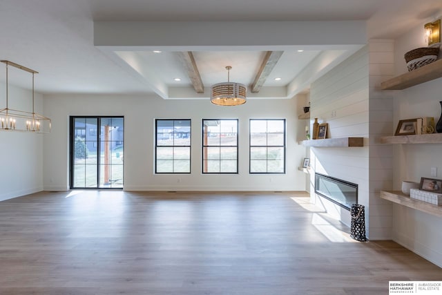 unfurnished living room with a notable chandelier, a large fireplace, and hardwood / wood-style flooring