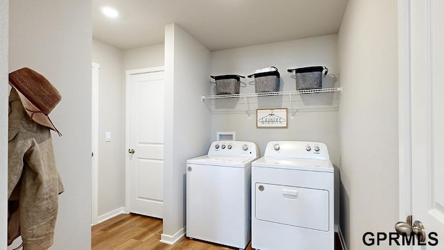 clothes washing area with light wood-type flooring and washer and clothes dryer