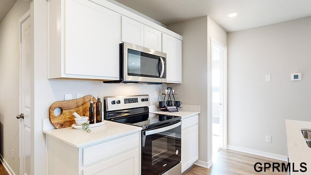 kitchen with white cabinets, stainless steel appliances, and light hardwood / wood-style flooring