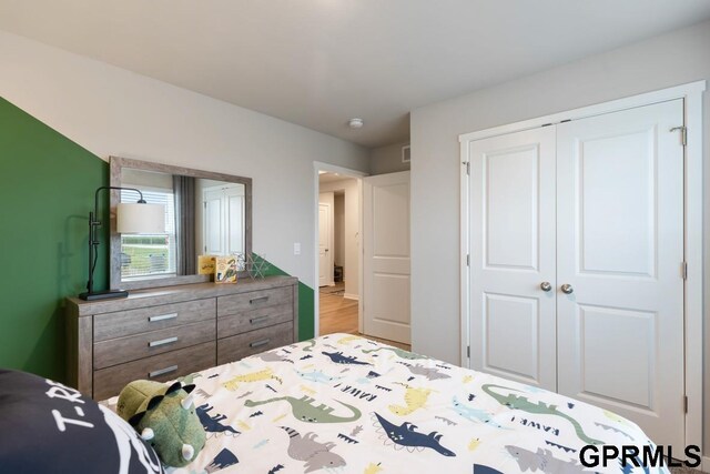 bedroom with light hardwood / wood-style floors and a closet