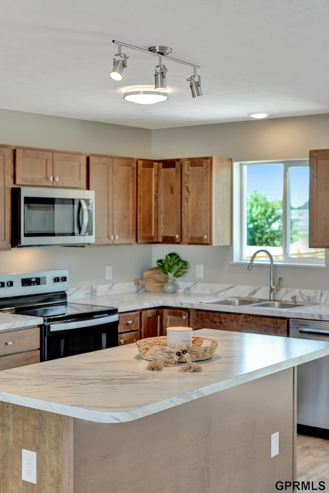 kitchen featuring sink, light hardwood / wood-style floors, pendant lighting, a kitchen island, and appliances with stainless steel finishes