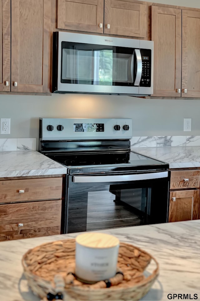 kitchen featuring black electric range, decorative backsplash, and light stone countertops