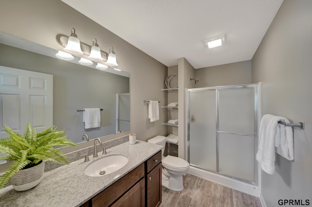 bathroom featuring toilet, vanity, wood-type flooring, and walk in shower