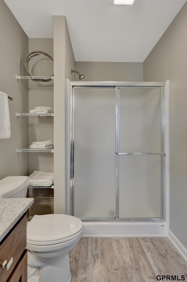 bathroom featuring hardwood / wood-style floors, vanity, toilet, and a shower with door